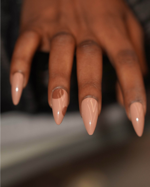 Sharp acrylic nails in glossy nude with two large brown polka dots.