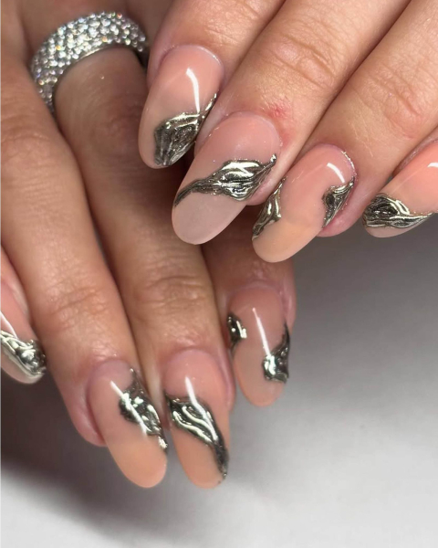 Roundshaped matte nude nails with raised silver chrome drip design.