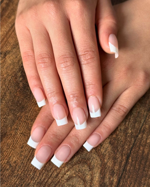 One hand layered flat on the other showing classic square cut French tip manicure.